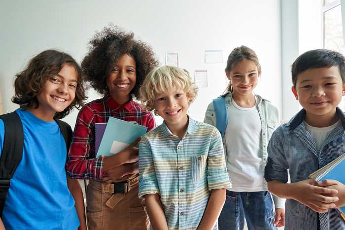 Several children holding books and wearing backpacks