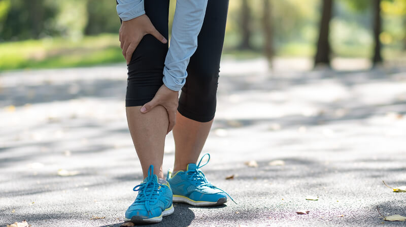 Person rubbing painful legs during an outing.